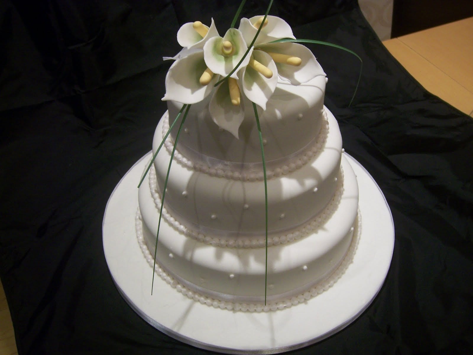 3 tier white wedding cake with sugar lilies and edible white pearls