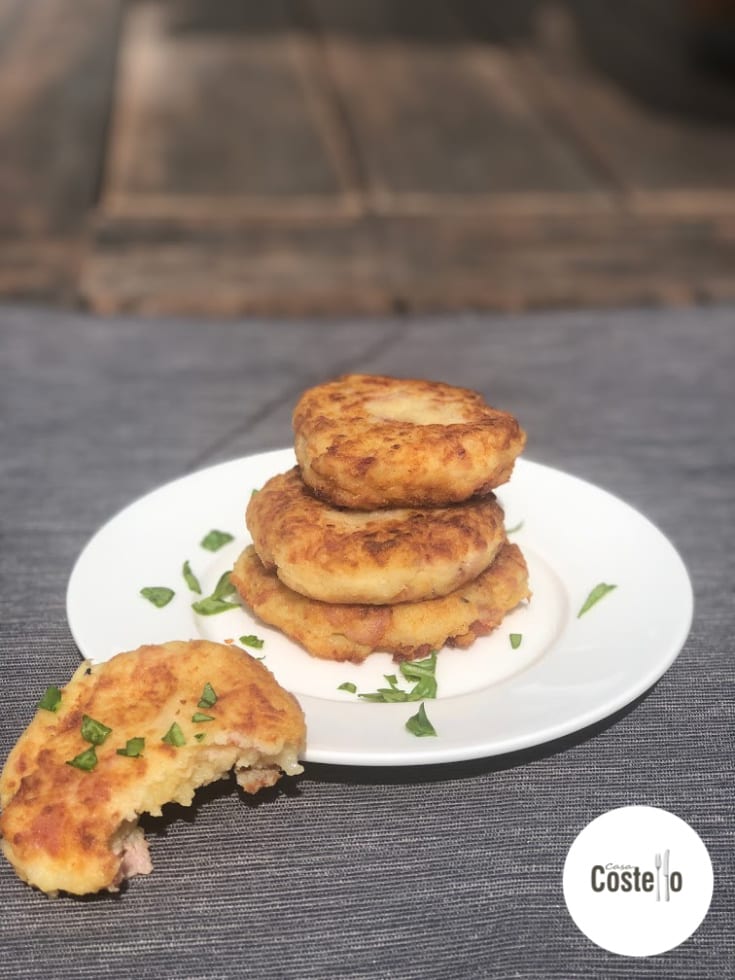 Piri Piri Potato Cakes in a stack with bacon pieces and chopped herb decorations
