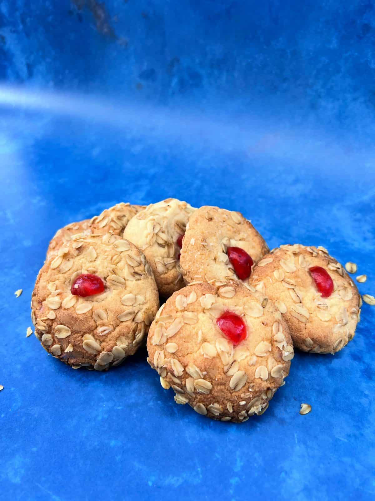A selection of melting moments cookies on a blue background with oats scattered around.