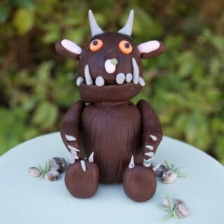 Chocolate gruffalo edible cake topper sitting on top of a pale blue cake