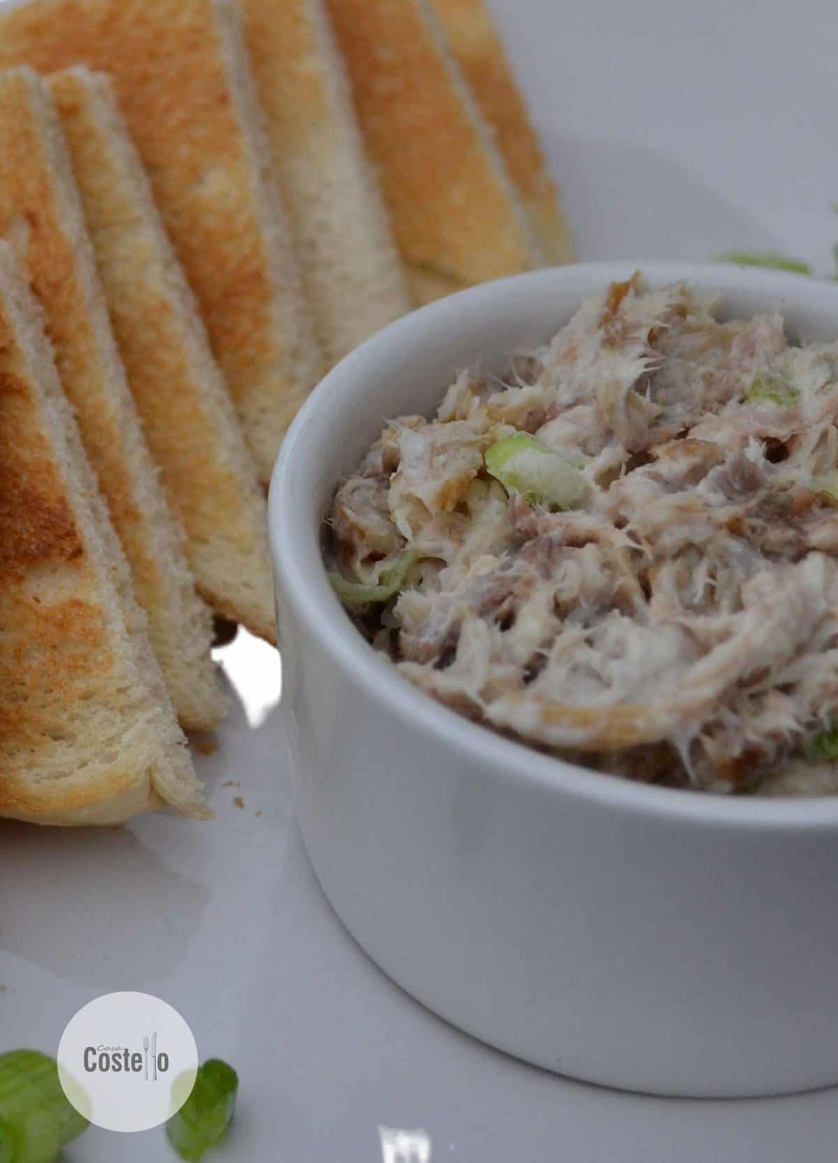 mackerel pate in a round white bowl with triangles of toast stacked next to it