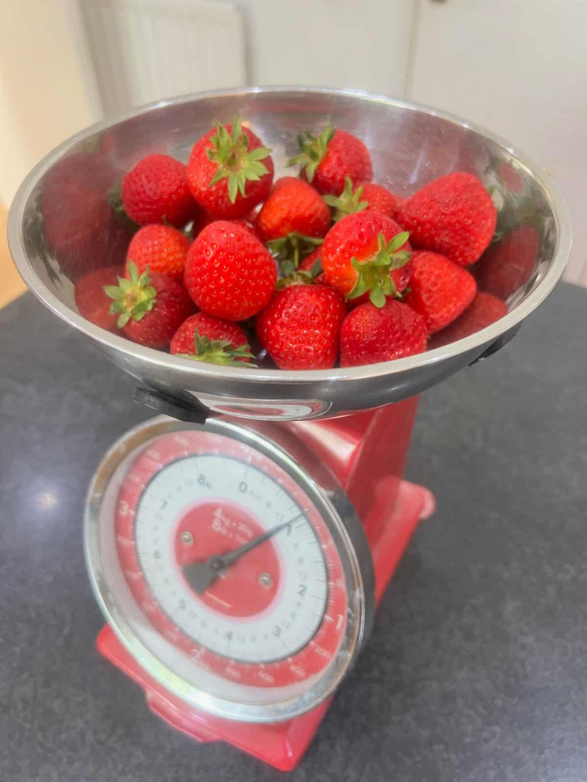 strawberries being weighed on a set of red scales