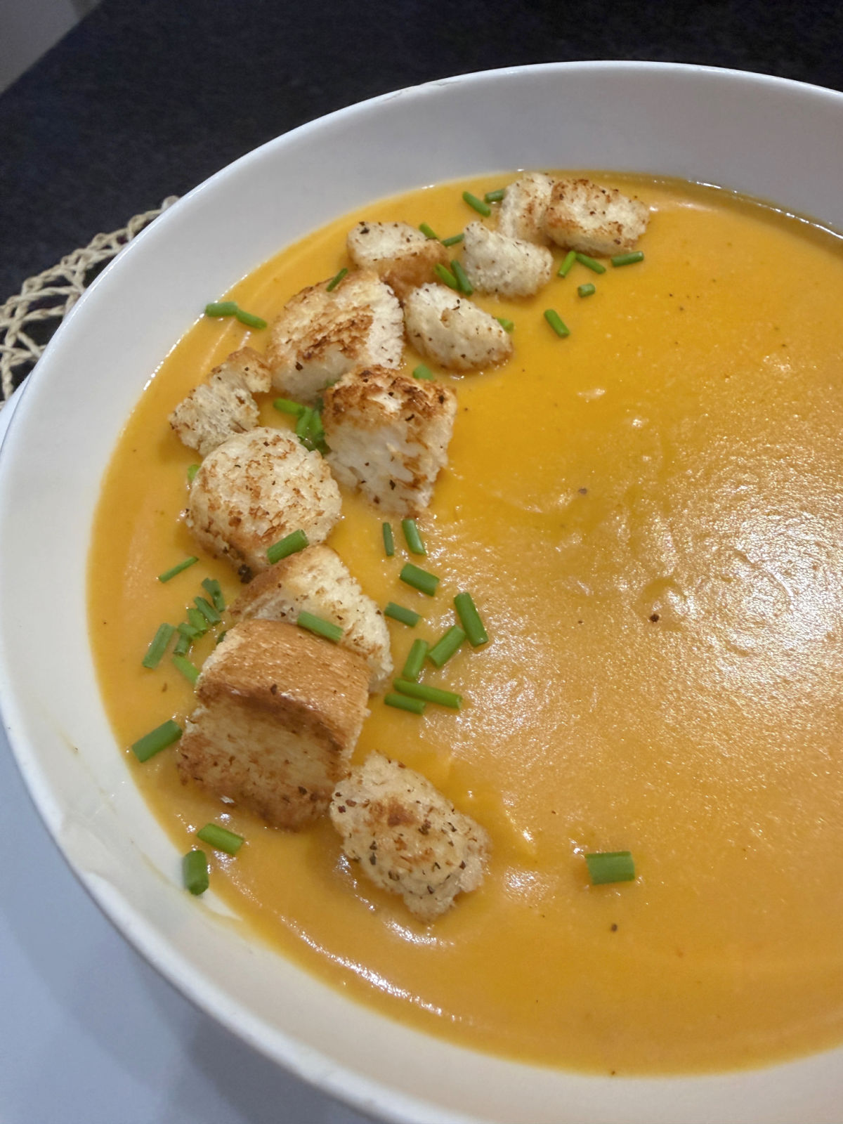 Sweet Potato and lentil chilli soup with homemade croutons and chives in a white bowl