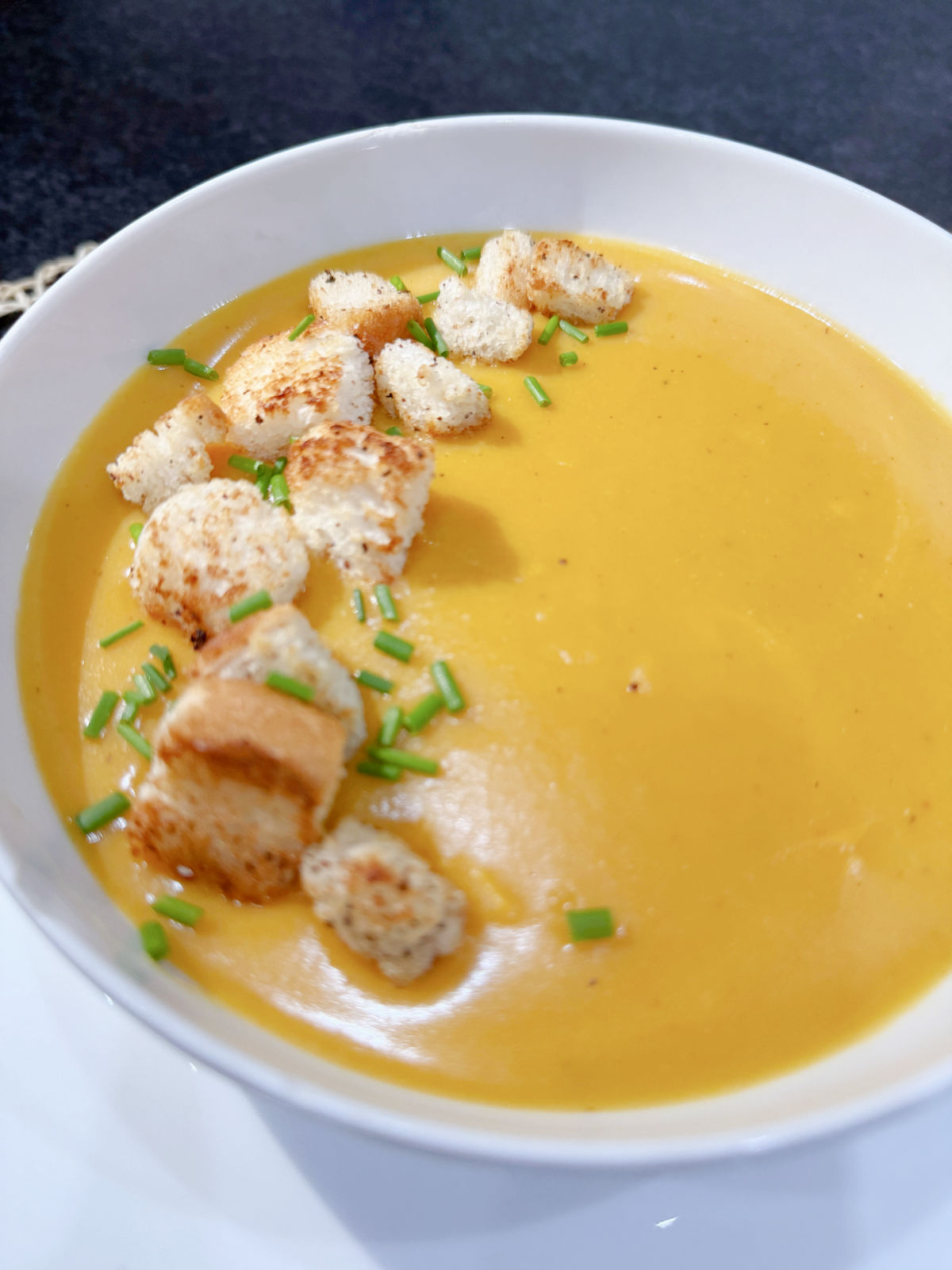 Sweet Potato and Lentil Soup with Chilli, homemade croutons and chives in a white bowl