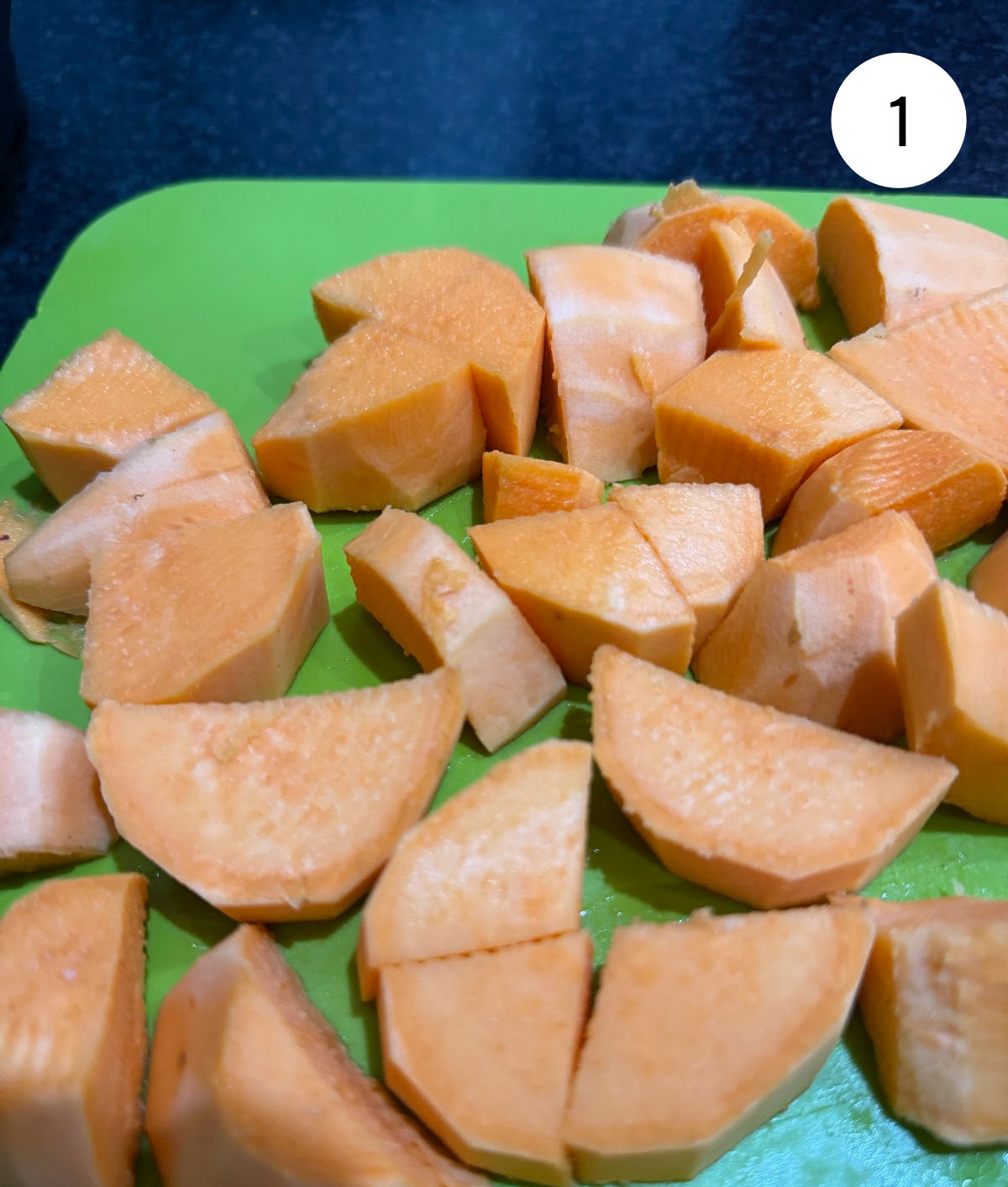 Chopped and peeled sweet potatoes on a green chopping board